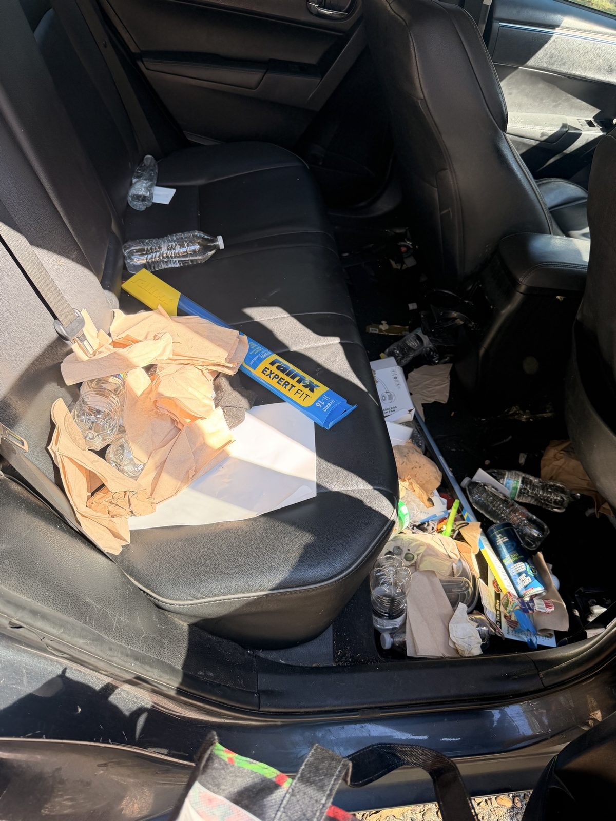 Toyota Corolla back seat covered with trash before detailing